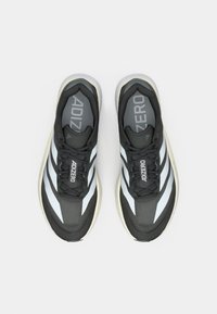 Mustat urheilu kengät harmailla yksityiskohdilla, joissa on verkkomateriaali, kolme valkoista raitaa ja pehmeä pohja. Brändin nimi "ADIZERO" on näkyvissä.
