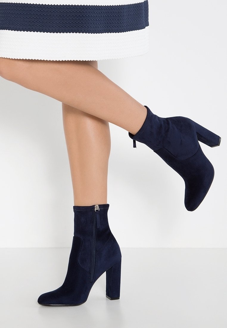 Bottines bleu marine en daim doux, dotées d'un talon épais, d'une fermeture éclair latérale et d'un design élégant et épuré.