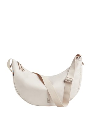 Beige Umhängetasche mit geschwungenem, weichem Design. Hergestellt aus glattem Material, verfügt über einen verstellbaren Riemen und zwei Reißverschlussfächer.