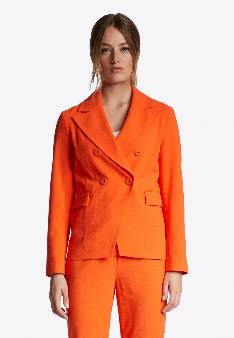 Oranje dubbelzijdige blazer met een textuurafwerking, geknipte revers en twee voorzakken, gestyled met bijpassende broek.