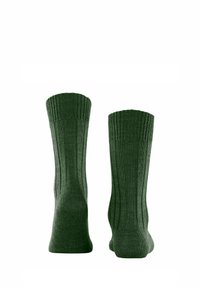 Ein Paar dunkelgrüne, gerippte Socken im Crew-Stil, aufrecht auf einem weißen Hintergrund präsentiert.