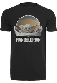Juodas medvilnės marškinėliai su grafika, kurioje pavaizduotas žalias veikėjas ankštyje, o žemiau didžiosiomis baltomis raidėmis yra užrašas "THE MANDALORIAN".