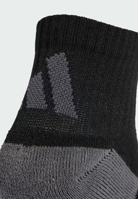 Calcetines de lana en negro y gris con un patrón texturizado. Presentan una parte superior negra sólida y una sección gris con un diseño de logotipo sutil.