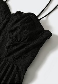 Černý krajkový oděv s nastavitelnými ramínky, který má texturovaný květinový vzor a nařasené detaily podél korzetu. Měkký a prodyšný materiál.