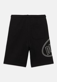 Μαύρο σορτς μήκους έως το γόνατο με ελαστική μέση, τσέπη με μπαλώματα στο πίσω μέρος και μερικό λευκό περίγραμμα κειμένου στο δεξί πόδι.