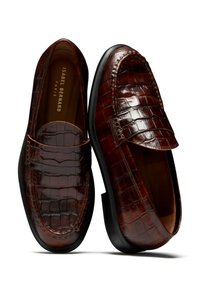 Bruine leren loafers met krokodillenprint, voorzien van een verhoogde achterkant en een klassieke pennystrap. Soepele binnenkant en een platte zwarte zool.