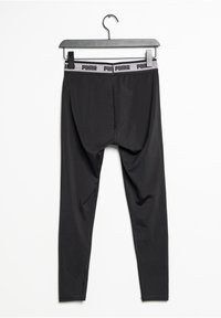 Leggings atletici neri con una texture morbida, dotati di un waistband elastico con logo e una vestibilità aderente, appesi a una gruccia nera.