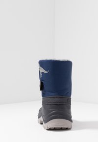 Botte étanche bleu marine avec une surface texturée, une semelle en caoutchouc grise, un col doublé en polaire et un logo dinosaure à l'arrière.