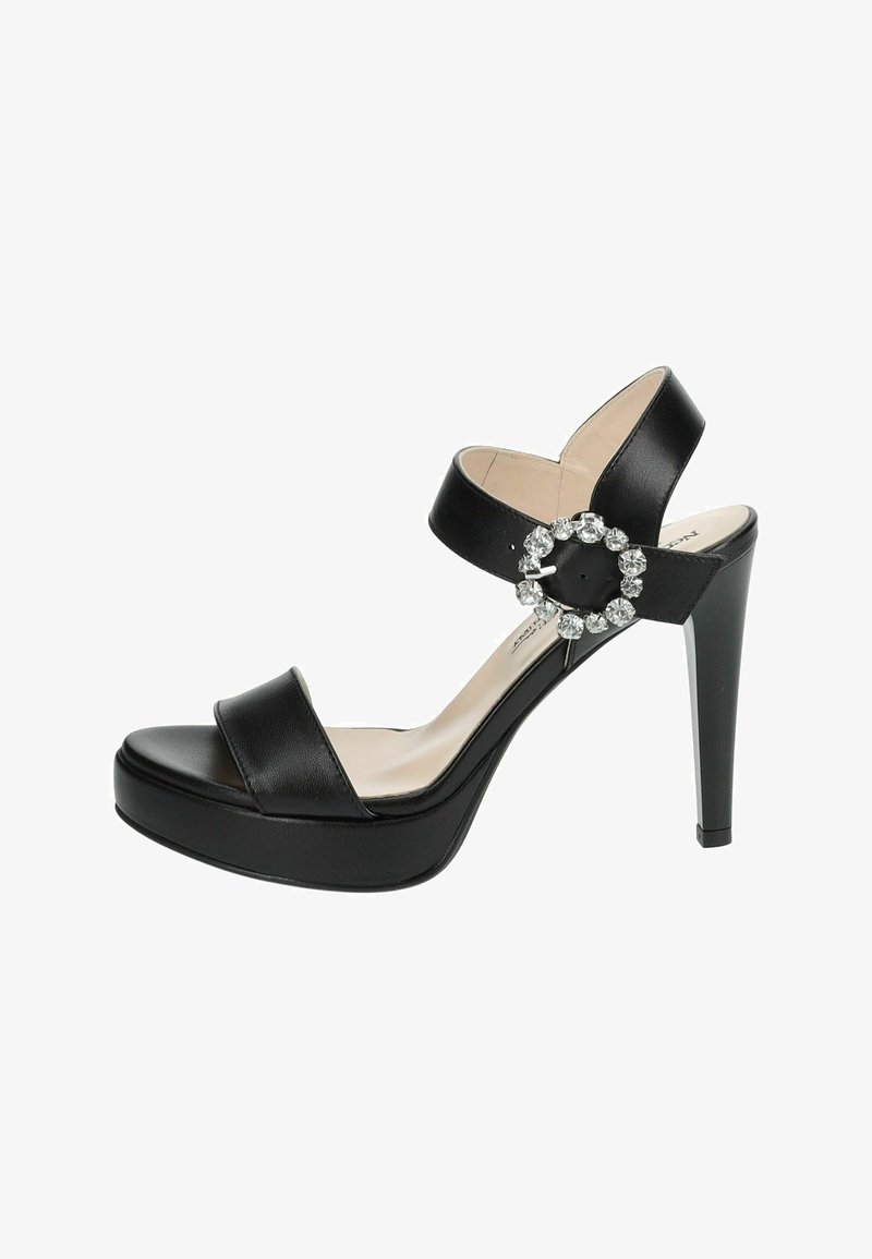 Sandales à talons hauts en cuir noir avec une plateforme, dotées de deux sangles sur le pied et d'un accent en bijou circulaire sur la sangle de la cheville.
