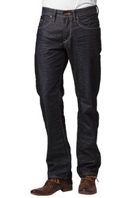 Mörkblå denimjeans med rak skärning, kontrasterande orange sömmar och femficksdesign. Används med bruna texturerade snörskor.