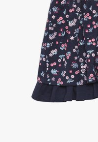 Marineblauwe jurk met bloemenpatroon in roze en blauw, voorzien van korte mouwen en een geplooide zoom met ruches. Gemaakt van zachte katoen stof.