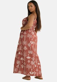 Maxime dress in terrakotta med hvit palmeblad mønster, med tynne stropper og en avslappet passform, laget av lett stoff.