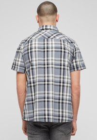Košeľa s krátkym rukávom s károvaným vzorom v sivých, čiernych a bielych farbách. Má golier na gombíky a zadný diel s chrbtovou vsadkou. Ľahká látka s károvaným vzorom.