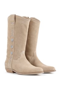 Bottes beige en daim montantes avec un bout pointu, dotées de boutons en argent décoratifs et d'accents en clous sur le côté. Talon en bois.