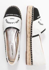 Espadrillas in bianco e nero con tomaia in tela, suola intermedia in juta intrecciata e dettagli metallici. Presentano il marchio sul cappuccio del piede.
