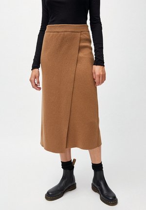 Jupe portée mi-longue marron à ceinture côtelée, présentée avec un haut noir à manches longues et des bottines noires, ayant une texture lisse semblable à de la laine.