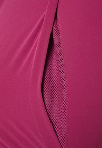 Κοντινό πλάνο ενός ματζέντα ενδύματος που δείχνει μια λεπτομέρεια από πάνελ με ανάγλυφη πλέξη για αναπνοή και αερισμό.