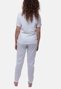 Hvid bomulds loungewear sæt bestående af en kortærmet top og bukser med elastiske manchetter. Glat tekstur, afslappet pasform, enkelt design.