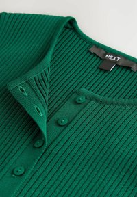 Zelený žebrovaný pletený cardigan s V-výstřihem, který má pět odpovídajících knoflíků a štítek s nápisem "NEXT" na vnitřním límci.