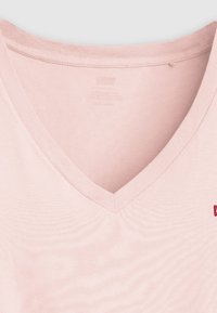 Ροζ ανοιχτόχρωμο t-shirt με V λαιμόκοψη, κατασκευασμένο από απαλή βαμβακερή ύφανση, με ριμπ λεπτομέρεια στη γραμμή του λαιμού και μικρό κεντημένο λογότυπο στο στήθος. Ομαλή υφή.