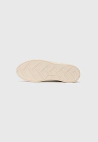 Suola di una sneaker beige con un motivo a righe geometriche, misura 36, e il nome del marchio "Tamaris" impresso vicino all'arco.
