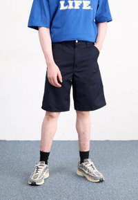 Blue cotton t-shirt with "LIFE." printed in white, paired with navy knee-length shorts. Worn with gray and black athletic shoes and black socks.