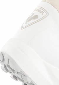 Witte sneaker met een textuur oppervlak, rubberen buitenzool met een opvallend profiel, en een subtiele grijze logo aan de zijkant.