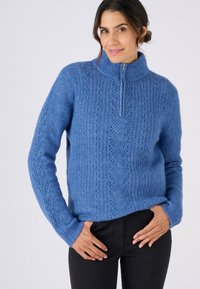 Maglione blu lavorato a maglia con collo alto e zip parziale, caratterizzato da un motivo testurizzato e polsini a coste. Materiale morbido e caldo.