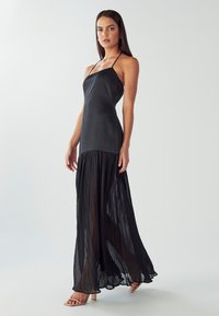 Schwarzes Maxikleid mit einem Satin-Oberteil und einem plissee Chiffonrock. Verfügt über verstellbare Träger und ein fließendes Design, das eine geschichtete Textur erzeugt.