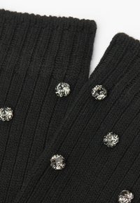 Guanti neri a coste in maglia con cinque strass trasparenti incastonati in un motivo simmetrico sulla parte esterna per un tocco decorativo.