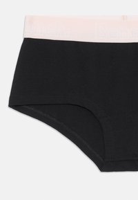 Črne bombažne hlačke tipa boyshorts z na svetlo roza elastiko, ki nosi logotip. Gladka tekstura, ravni kroj in minimalni detajli šivanja.