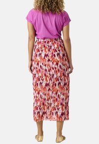 Kleurvolle bloemenprint geplooide maxi rok in tinten van roze, oranje en wit, gecombineerd met een roze top met korte mouwen. Zachte stoftextuur.