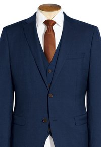 Veste de costume bleu marine avec des revers à cran, une poche poitrine et deux poches avant, associée à une cravate marron à motifs et une chemise blanche.