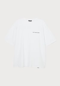 Hvid bomulds t-shirt med korte ærmer, der har et lille sort teksttryk på venstre side, som siger "spild ikke kulturen."