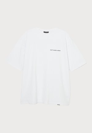 Hvid bomulds t-shirt med korte ærmer, der har et lille sort teksttryk på venstre side, som siger "spild ikke kulturen."