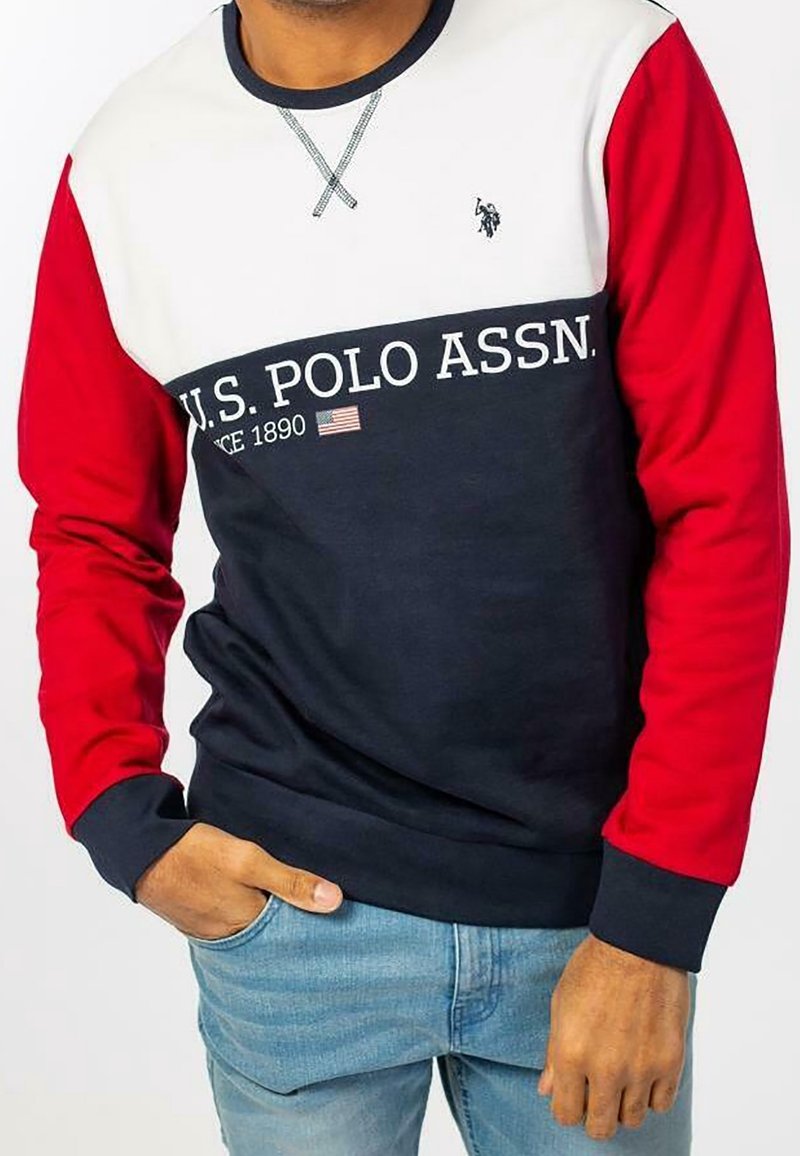 Marinblå, vit och röd långärmad sweatshirt med rundad halsringning. Har texten "U.S. POLO ASSN.", en accent av den amerikanska flaggan och ribbade ärmslut.