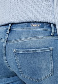 Bleknade blå denimjeans med en medelhög passform, med bakfickor och en märkesläderpatch på midjebandet.