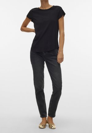 Black short-sleeve top paired with dark jeans and gold flats. Smooth fabric, relaxed silhouette, and round neckline. Simple and versatile design.