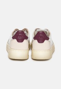Sneaker bianchi e beige con un tab in maroon sul tallone. Materiali in pelle e suede texture, punta arrotondata e suola in gomma.