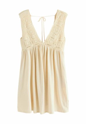 Helle beige ärmelloses Kleid mit tiefem V-Ausschnitt, gehäkeltem Quadratmuster an den Schultern und rüschenförmig fallendem Stoff von der Taille.
