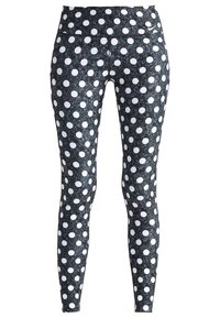 Leggings negros con un acabado texturizado, con grandes lunares blancos dispuestos de manera uniforme a lo largo de la tela. Diseño de cinturilla suave.