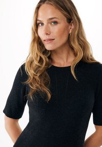 Černý úpletlý top s krátkými rukávy a kulatým výstřihem, vyrobený z texturované látky s přiléhavým střihem.