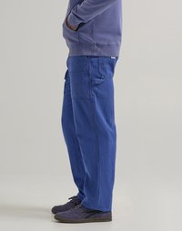 Blue corduroy cargo pants with a loose fit, featuring side pockets and a ribbed texture, paired with dark purple sneakers.