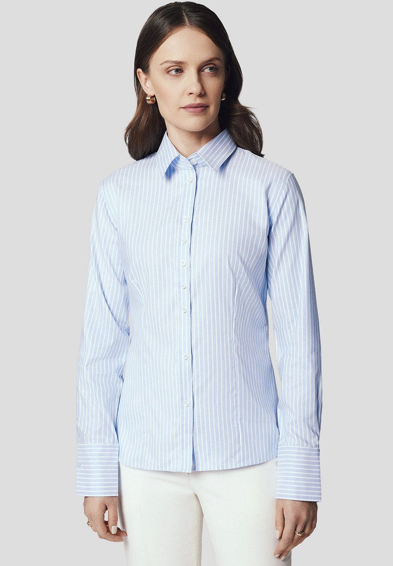 Jasnoniebieska, w paski koszula zapinana na guziki z długimi rękawami, kołnierzykiem i białymi guzikami. Gładki materiał, kontrastujące paski i szerokie mankiety.
