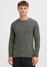 Pulover cu maneci lungi dintr-un tricot gri texturat, având un gât rotund și manșete ajustate. Vârful plat și detalii minime.