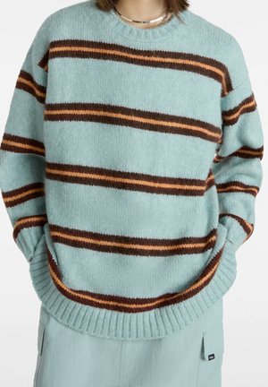 Jasnoniebieski sweter z dzianiny z szerokimi poziomymi paskami w ciemnym brązie i pomarańczowym. Ściągacze przy mankietach i u dołu oraz dekolt typu crew neck.