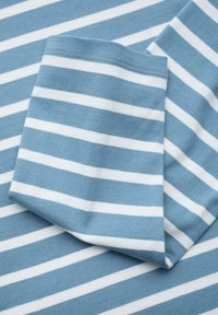 Modrá a bílá pruhovaná bavlněná tkanina s horizontálními pruhy; měkká textura a detail ohrnutého rukávu v rohu.