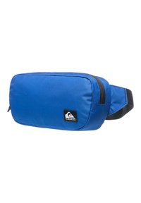 Sininen vyölaukku, joka on valmistettu hauskan tekstuurin omaavasta nailonista, varustettuna vetoketjulla, mustalla logo-patchilla ja säädettävällä hihnalla. Kompakti, suorakulmainen muotoilu.