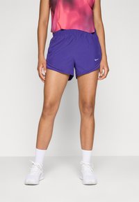 Os calções atléticos roxos da Nike apresentam uma cintura elástica e um tecido leve e respirável. O modelo combina com ténis e meias brancas.