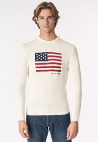 Maglione bianco lavorato a maglia con un design della bandiera americana sul petto, con accenti rossi e blu e polsini e orlo a coste.